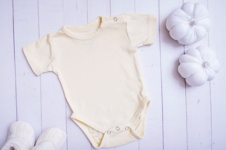 Yellow baby bodysuit mockup on wooden background with pumpkins top viewの写真素材