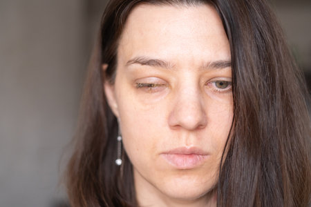 A woman with long dark hair gazes seriously into the distance. The soft indoor lighting highlights...