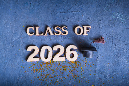Class of 2026 with graduate hat on dark blue background with tinsel.