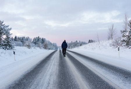 Image of man walking away on winter roadの写真素材