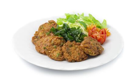 Thai Fish Cake Paste chili deep fried with herb and Crispy Thai Basil. Thai Food dish style decorate with carved carrots flower shape and tomato side viewの写真素材