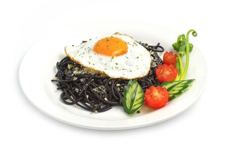 Spaghetti stir fried with garlic and parmesan cheese on top with Fried egg fusion food Italian traditional style mix Thai food style decorate with tomato and cucumber side viewの写真素材