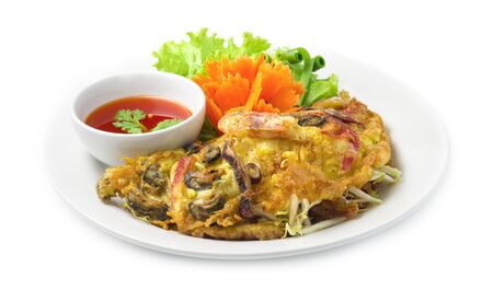 Crispy Seafood fried Pancake fusion Thai food and Chinese food style and chili sauce dipping inside dish decorate with carved carrots flowers ,green leaf salad vegetable side viewの写真素材