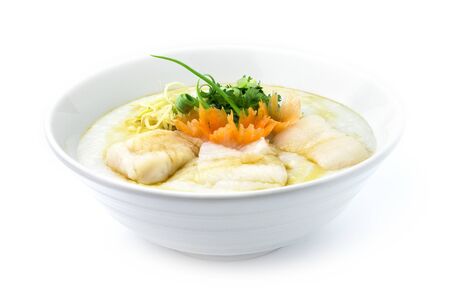 Congee Fish Asian Seabass ,Rice Porridge served slice ginger and cutlet Celery,coriander thai herb. Asian Food breakfast decorate with carved carrots and spring onio side viewの写真素材