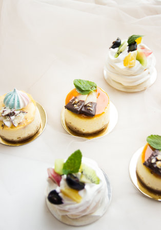 This stock photo shows a set of mini cheesecakes and Italian meringue decorated with fruits.の写真素材