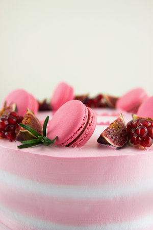 This stock photo shows a pink cake decorated with meringue Italian macaroons, figs, rosemary, and garnet.の写真素材