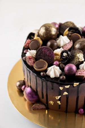 This stock photo shows a chocolate cake decorated with colorful cookies, chocolate sweets, and Italian meringue.の写真素材