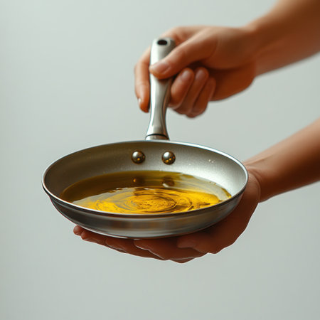 A hand holds a frying pan filled with glistening oil, ready for cooking adventures.の素材