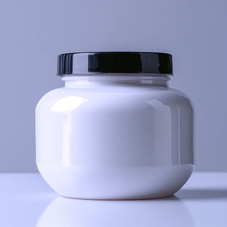 A white jar with a sleek black lid rests on a clean surface.の素材
