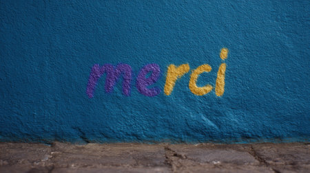 A vibrant wall features a colorful 'merci' on a stunning blue backdrop.の素材