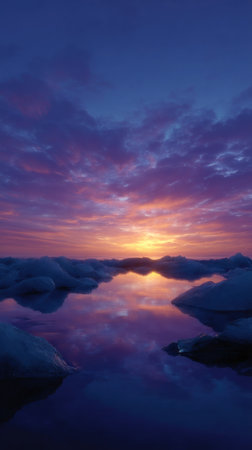 Breathtaking hues paint the sky as the sun sinks, illuminating the tranquil water and ice.の素材