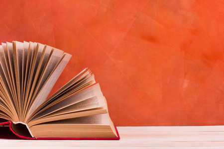 Composition with vintage old hardback books, diary, fanned pages on wooden deck table and red background. Books stacking. Back to school. Copy Space. Education backgroundの写真素材