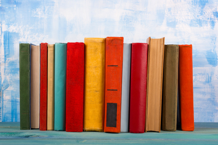 Composition with old vintage colorful hardback books, diary on wooden deck table and artistic blue background. Books stacking. Back to school. Copy Space. Education backgroundの写真素材