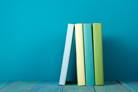 Row of books, grungy blue background, free copy space Vintage old hardback books on wooden shelf on the deck table, no labels, blank spine. Back to school. Education backgroundの写真素材