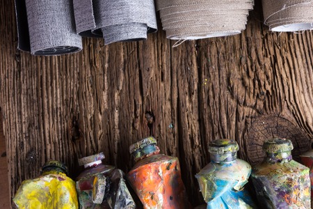 Vintage stylized photo of oil multicolor paint tubes closeup and artist paintbrushes on wooden desk. Top view.の写真素材