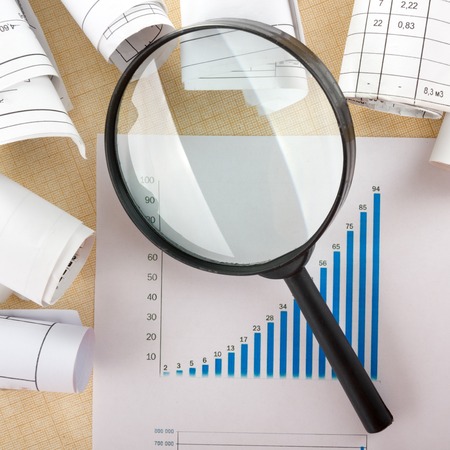 Search with magnifying glass in books, blueprints, magazines looking for information. Audit inspection. Copy space for text. Isolated on white backgroundの写真素材