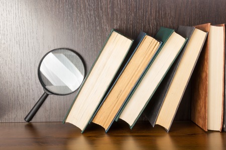 Stack of books with magnifying glass. Search informationの写真素材
