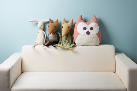 Home interior. Childhood. Blue background. Toy sitting on a couch. Copy space