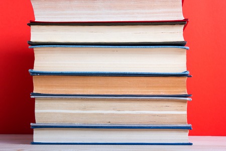 Composition with vintage old hardback books, diary, fanned pages on wooden deck table and red background. Books stacking. Back to school. Copy Space. Education background.の写真素材