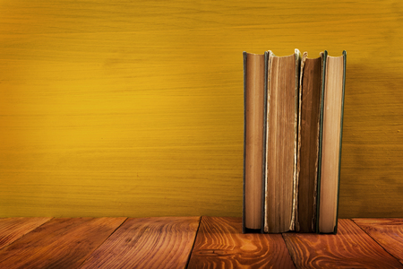 Colorful composition with vintage old hardback books, diary on wooden deck table and yellow background. Books stacking. Back to school. Copy Space. Education backgroundの写真素材