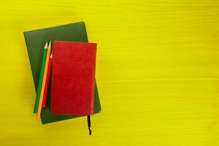 Colorful composition with vintage old hardback books, diary on wooden deck table and yellow background. Books stacking. Back to school. Copy Space. Education backgroundの写真素材