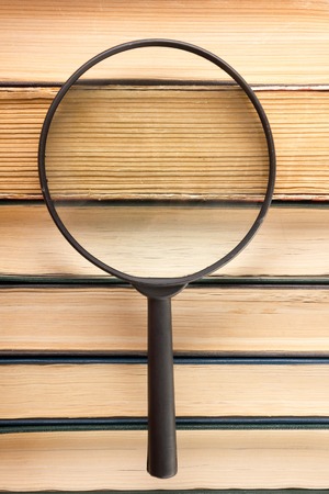 Stack of books with magnifying glass. Search informationの写真素材