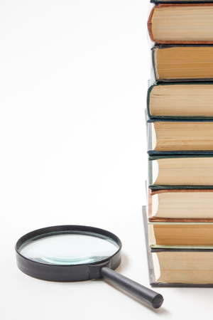 Search with magnifying glass in books, blueprints, magazines looking for information. Audit inspection. Copy space for text. Isolated on white backgroundの写真素材