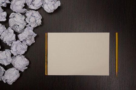 Crumpled paper balls and blank sheet of paper with pencil on black background. Paper wad. Creativity...