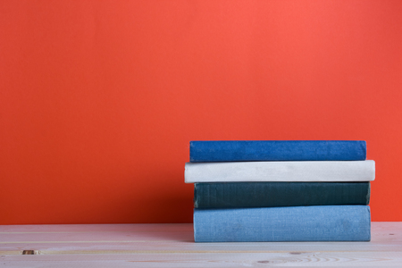 Composition with vintage old hardback books, diary, fanned pages on wooden deck table and red background. Books stacking. Back to school. Copy Space. Education background.の写真素材