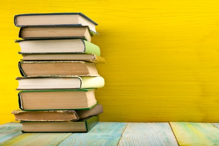 Colorful composition with vintage old hardback books, diary on wooden deck table and yellow background. Books stacking. Back to school. Copy Space. Education backgroundの写真素材