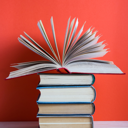 Composition with vintage old hardback books, diary, fanned pages on wooden deck table and red background. Books stacking. Back to school. Copy Space. Education background.の写真素材