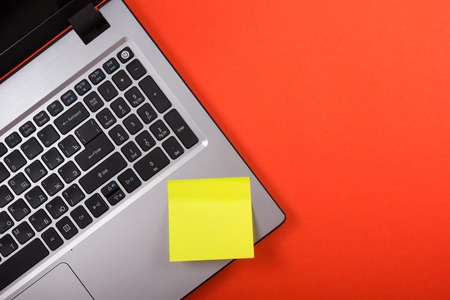 Office table desk with set of colorful supplies, laptop and reminder sticky note on red background. Top view. Copy space for text.の写真素材
