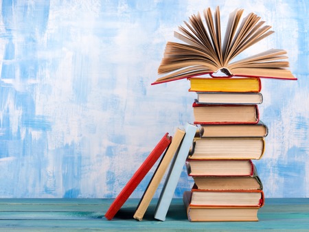 Composition with old vintage colorful hardback books, diary on wooden deck table and artistic blue background. Books stacking. Back to school. Copy Space. Education backgroundの写真素材