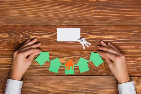 Paper house figure and blank business card on wooden background. Real Estate Concept. Top view.の写真素材