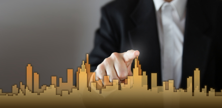 Businessman Activate Growth Process, choosing house, real estate city concept. Skyline Hand pressing the house icon on virtual screen. Business, technology, internet and networking concept. Copy space.の写真素材