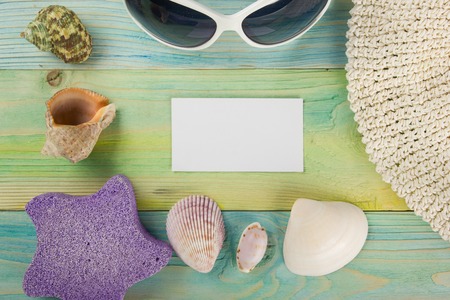 Summer sea vacation background with white blank business card Notebook blank page with Travel items on blue green wooden table. Sea shells, pebbles, top view mockupの写真素材