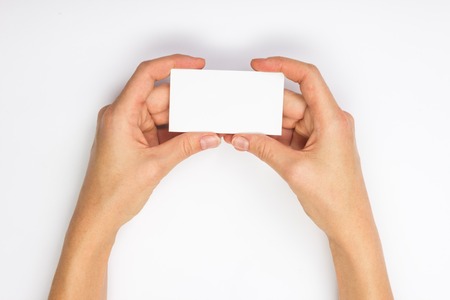 Hand holding white blank business card on blue blurred background. Copy spaceの写真素材
