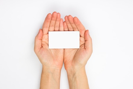 Hand holding white blank business card on blue blurred background. Copy spaceの写真素材