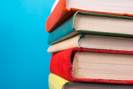 Stack of colorful books, grungy blue background, free copy space Vintage old hardback books on wooden shelf on the deck table, no labels, blank spine. Back to school. Education backgroundの写真素材