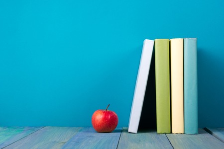Row of books, grungy blue background, free copy space Vintage old hardback books on wooden shelf on the deck table, no labels, blank spine. Back to school. Education backgroundの写真素材