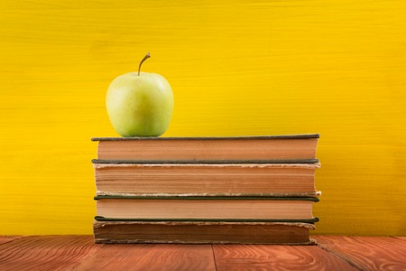 Colorful composition with vintage old hardback books, diary on wooden deck table and yellow background. Books stacking. Back to school. Copy Space. Education backgroundの写真素材