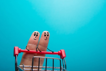 Funny fingers shopping at supermarket with red trolley on blue background.の写真素材