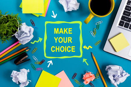 Make your choice. Office table with notepad, computer and coffee cup on blue background. Business creative consept top viewの写真素材