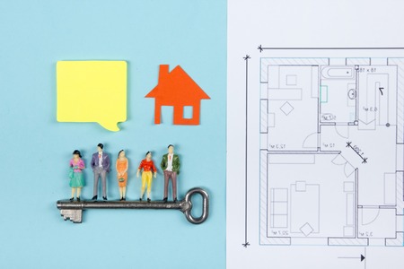Real Estate concept. Construction building. Blank speech bubbles, people toy figures, paper model house, blueprints with key on blue architect desk table background. Top view. Copy space for ad textの写真素材