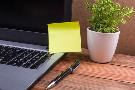 Office table desk with supplies, white blank note pad, cup, pen, pc, crumpled paper, flower on wooden background. Top viewの写真素材