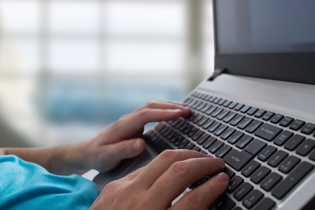 Mans hands typing on laptop notebook keyboard in the office. Man browsing information on internet. Freelance blogging, it support conceptの写真素材