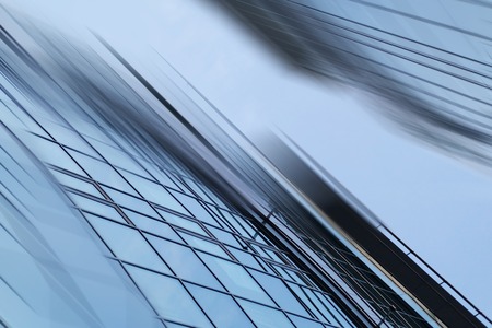 Abstract business modern city urban futuristic architecture background. Real estate concept, motion blur, reflection in glass of high rise skyscraper facade, toned blue picture with bokehの写真素材