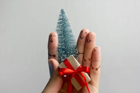 Funny fingers faces present gift box against blue background. Happy family celebrating concept for Christmas or New Years dayの写真素材