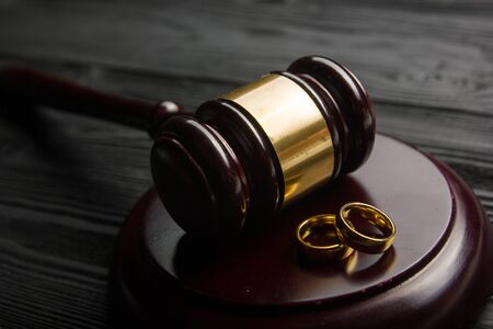 Divorce and separation concept. Two golden wedding rings, judge gavel.の写真素材