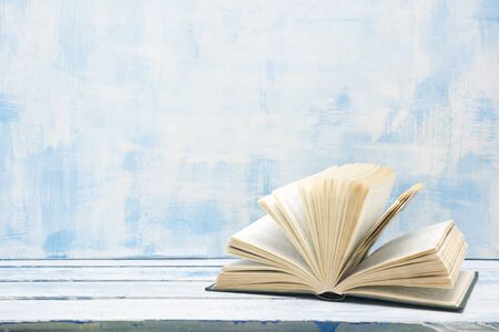 Composition with vintage old hardback books, diary, fanned pages on wooden deck table and red...